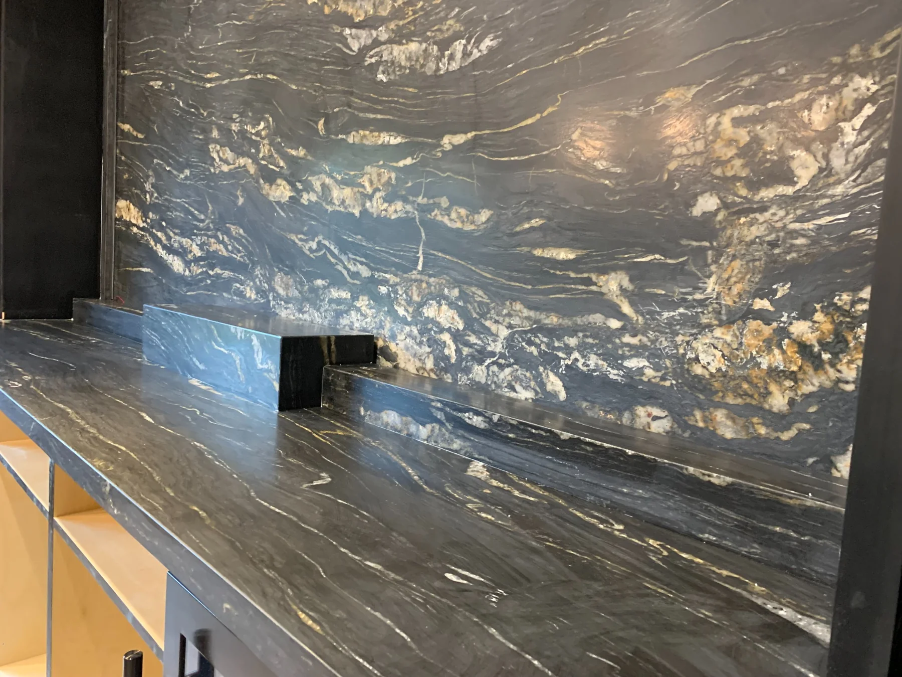Close-up of a Black Absolute leather-finish backsplash and countertop installation