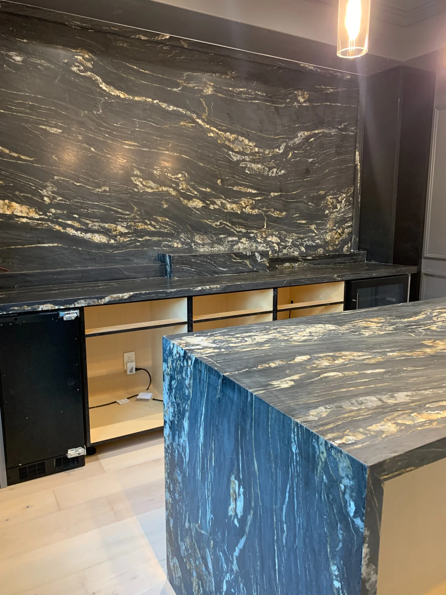 Wide view of a Black Absolute leather-finish feature wall with matching countertop and island surfaces
