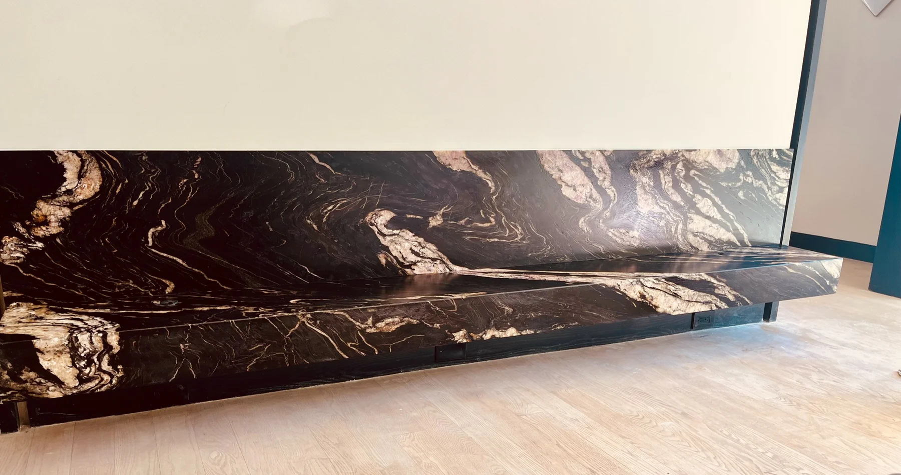 Floating Black Absolute leather-finish stone bench installation fabricated from a dramatic slab