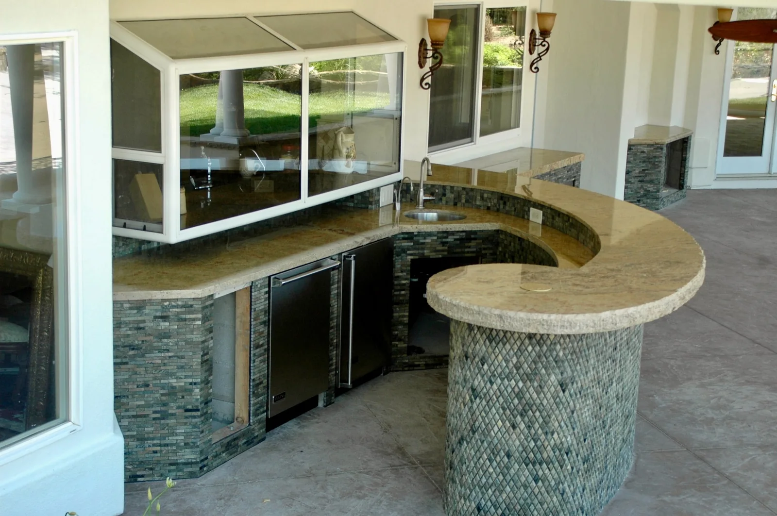 Curved outdoor kitchen stone countertop with sink and patio bar in Los Angeles