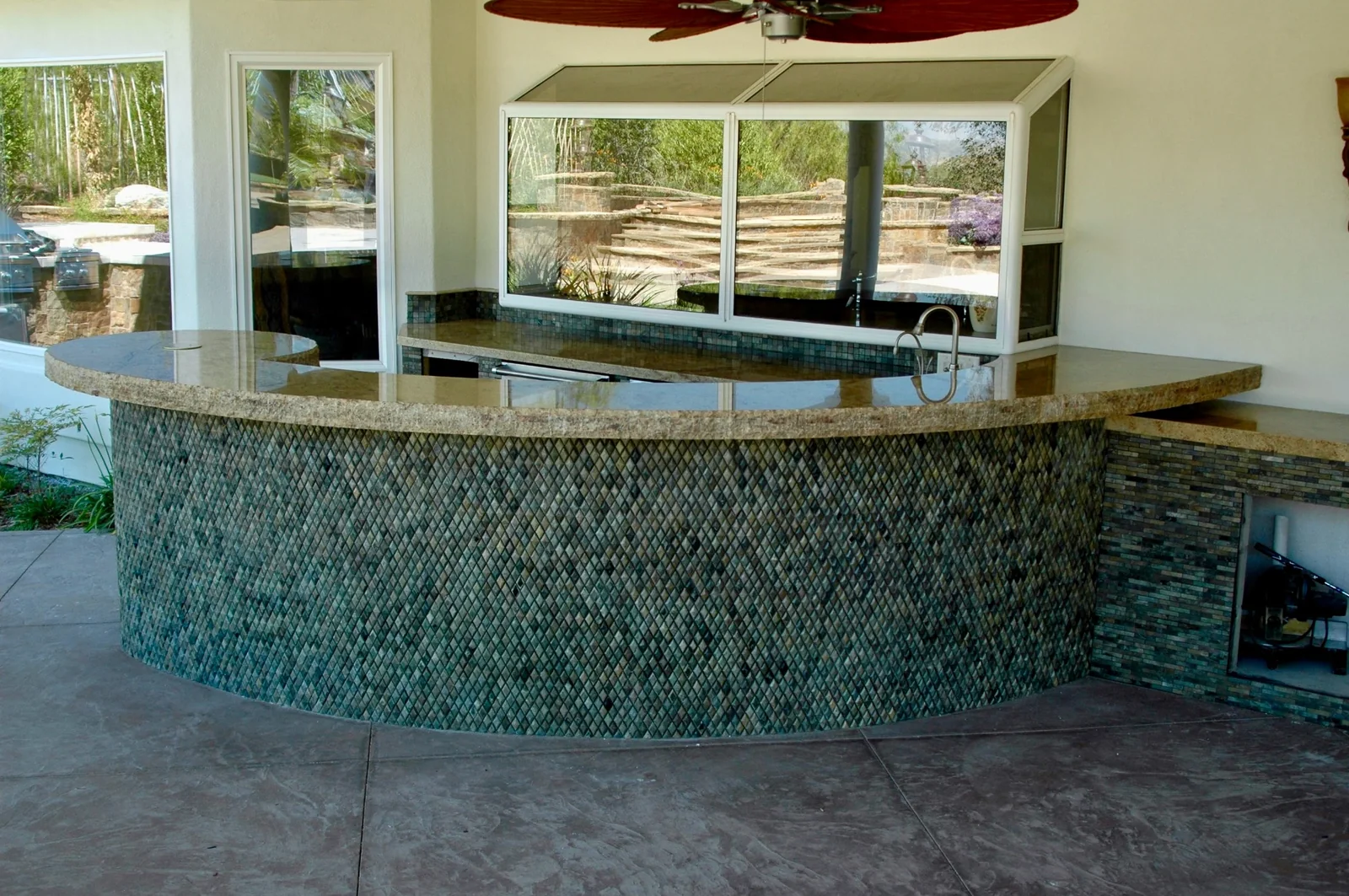 Wide view of custom curved outdoor stone bar countertop and exterior kitchen counter