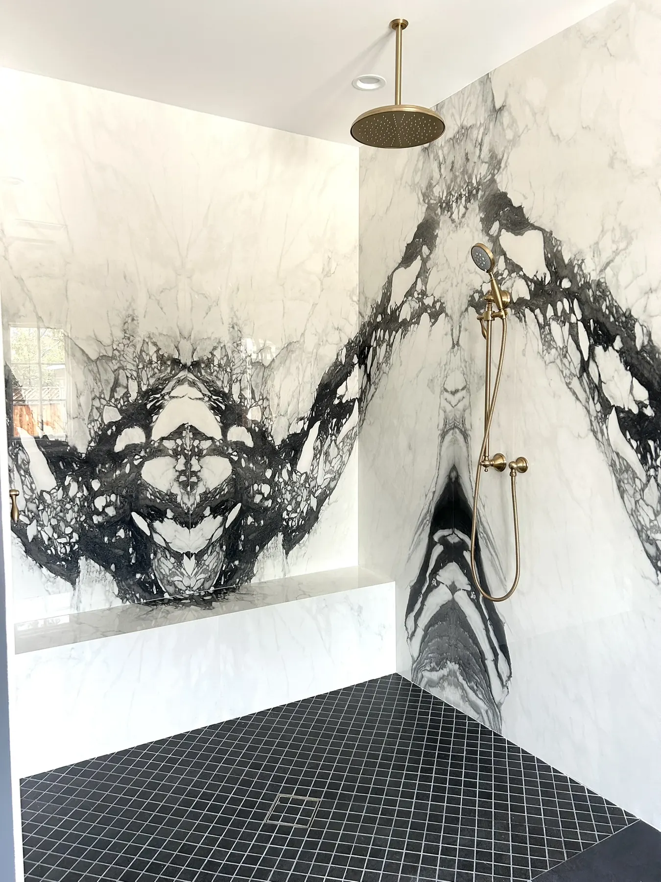 Finished Panda marble slab shower with bench and bookmatched wall