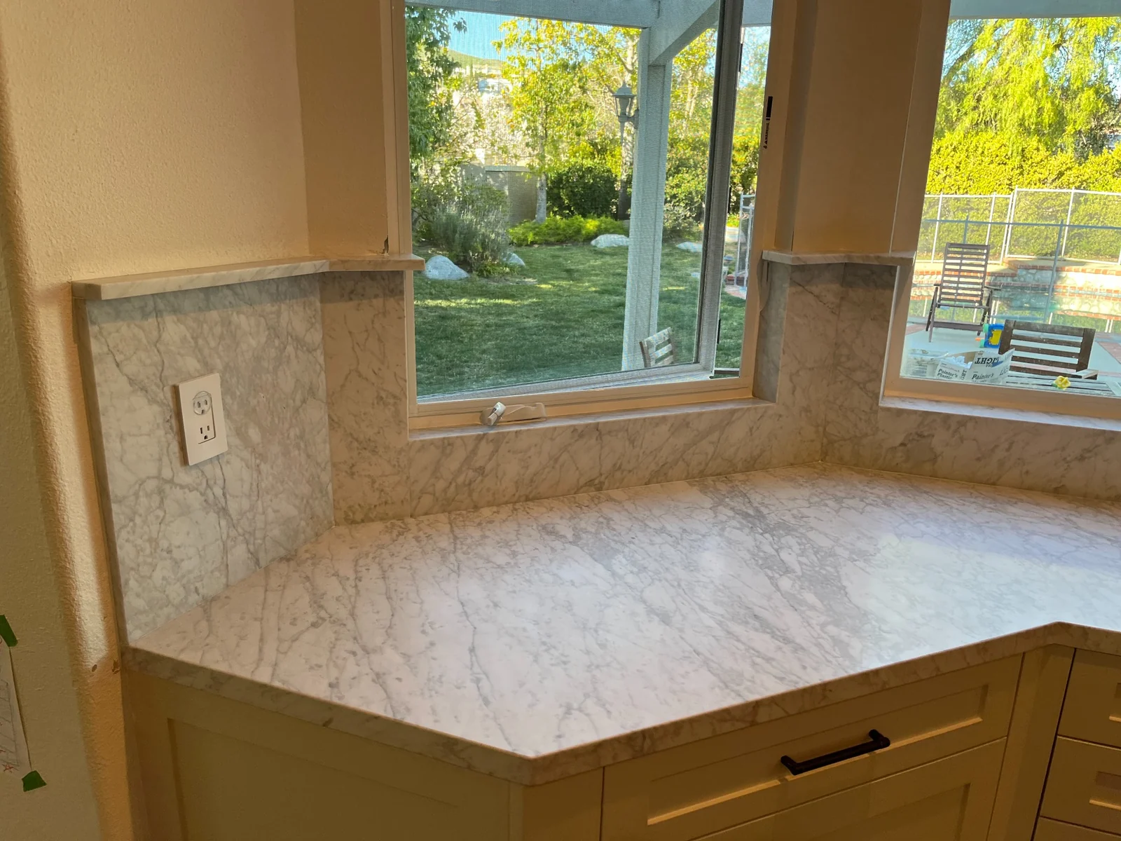 Bianco Carrara countertop below kitchen windows with short backsplash returns