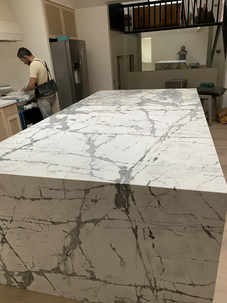 Finished white waterfall island countertop with bold grey veining